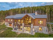 Stunning two-story home with a stone foundation and a backdrop of towering pine trees at 242 Point View Pl, Breckenridge, CO 80424