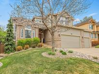 Charming two-story home featuring a manicured lawn, mature trees, and a brick facade at 7138 Mountain Brush Cir, Highlands Ranch, CO 80130