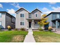 Charming two-story home with a well-manicured front yard and inviting curb appeal on a sunny day at 18060 E 106Th Pl, Commerce City, CO 80022