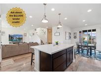 Bright open-concept living area with kitchen island and dining area, adjacent to a comfortable seating area with a large TV at 18060 E 106Th Pl, Commerce City, CO 80022