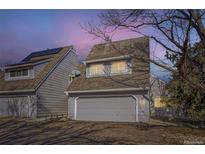 Charming two-story townhome with a single-car garage and grey siding at dusk at 10425 Red Mountain West, Littleton, CO 80127