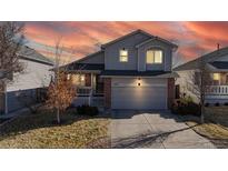 Charming two-story home with a two car garage and manicured front lawn set against a colorful sunset sky at 5436 S Versailles Way, Aurora, CO 80015