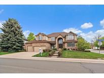 Inviting brick two-story home with manicured lawn, mature trees, and three-car garage at 7914 S Clayton Cir, Centennial, CO 80122