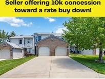 Charming two-story home featuring a brick facade, attached garages, and a well-manicured lawn at 9155 W Portland Ave, Littleton, CO 80128