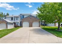 Two-story home featuring a two-car garage, mature tree, and well-manicured lawn in a suburban setting at 9155 W Portland Ave, Littleton, CO 80128