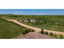 Expansive property featuring a charming home with beautiful landscaping and vast green fields on a sunny day at 29333 Rawhide Ct, Elizabeth, CO 80107