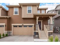 Inviting two-story home features a front-entry garage, covered porch, and neutral brown siding at 16432 Snowbourn Dr, Parker, CO 80134
