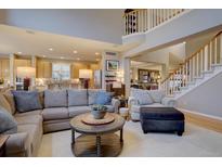 Open-concept living room featuring a comfortable sectional sofa and staircase to the second floor at 22921 E Euclid Cir, Aurora, CO 80016