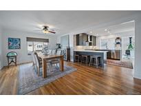 Open-concept dining room featuring hardwood floors, ceiling fan, and seamless flow into the modern kitchen at 3200 S Logan St, Englewood, CO 80113