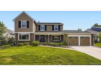 Charming two-story home featuring a well-manicured front lawn, brick accents, and a two-car garage at 5988 E Jamison Ln, Centennial, CO 80112