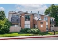 Charming condo building with red brick, beige siding, and well-maintained landscaping at 3550 S Harlan St # 214, Denver, CO 80235