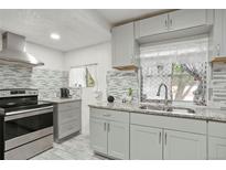 Bright kitchen features gray cabinets, granite countertops, mosaic backsplash, and stainless steel appliances at 1070 S Newton St, Denver, CO 80219