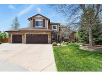 Beautiful two-story home featuring a three-car garage, stone accents, lush lawn, and mature trees at 9536 W Avalon Dr, Littleton, CO 80127
