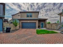 Two-story home featuring a blue garage door and quaint front lawn on a brick driveway at 17910 E 54Th Ave, Denver, CO 80249