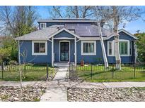 Charming blue home with solar panels, walkway, metal fence and lush trees at 2244 Fenton St, Edgewater, CO 80214