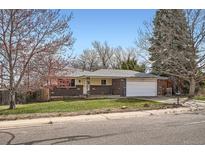 Charming single-story brick home with a well-manicured lawn and attached two-car garage on a sunny day at 798 Xenophon St, Lakewood, CO 80401