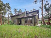 Charming two-story home with wood siding and well-maintained front yard surrounded by mature trees at 26765 Bradley St, Conifer, CO 80433