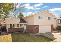 Charming home with a well-maintained lawn, brick accents, and an attached two-car garage at 6616 Zinnia St, Arvada, CO 80004