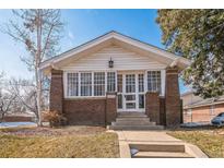 Charming brick home with a bright, sunlit front porch and well-manicured lawn at 2455 Lowell Blvd, Denver, CO 80211