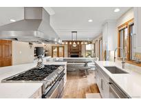 Gourmet kitchen boasts stainless appliances, large island, and opens to dining area with brick fireplace at 5034 E Otero Cir, Centennial, CO 80122