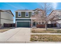 Charming two-story green home with a well-manicured lawn and attached two car garage at 5511 Kittredge St, Denver, CO 80239