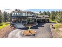 Stunning two-story home featuring stone accents, a covered front porch, and an expansive driveway with a circular turnaround at 230 S Big Meadow Trl, Franktown, CO 80116