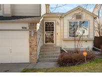 Inviting front entrance features a charming white door with glass, brick accents, and a well-maintained lawn at 9741 Moss Rose Cir, Highlands Ranch, CO 80129