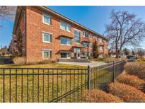 Brick apartment building featuring symmetrical design, large windows, and manicured landscaping with a black metal fence at 1201 Balsam Ave # 203, Boulder, CO 80304