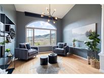 Elegant living room featuring a vaulted ceiling, large arched window, and mountain views at 415 Butte Pkwy, Golden, CO 80403