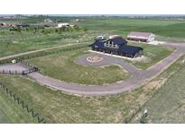 Expansive aerial view of home with circular driveway, dark metal roof, fenced perimeter, and green surrounding landscape at 3308 County Road 19, Fort Lupton, CO 80621
