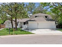 Charming home featuring mature trees, green lawn, and a spacious three-car garage at 6075 S Filbert Ct, Centennial, CO 80121