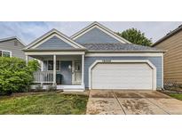 Charming exterior featuring blue siding, a front porch, an attached garage, and well-maintained landscaping at 12060 N Holly Way, Brighton, CO 80602