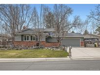 Charming single-story home boasts gray siding, brick accents, a manicured lawn, and an attached two-car garage at 7618 S Datura Cir, Littleton, CO 80120