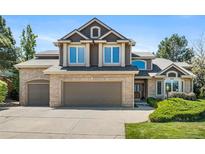 Charming two-story home featuring a brick and siding facade, a three-car garage, and manicured landscaping at 8833 Maplewood Dr, Highlands Ranch, CO 80126