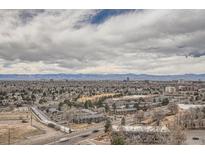 Expansive aerial view showcasing the city and the distant snow-capped mountains under a cloudy sky at 7865 E Mississippi Ave # 1501, Denver, CO 80247