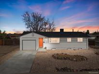 Charming single-story home featuring a vibrant orange front door and a well-maintained xeriscaped front yard at 306 N 14Th Ave, Brighton, CO 80601