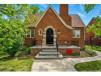 Charming brick home with arched doorway, black iron gate, and well-maintained landscaping at 2654 Forest St, Denver, CO 80207