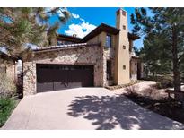 A beautiful stone home featuring a two-car garage and a long driveway at 8002 Galileo Way, Littleton, CO 80125