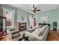 Charming living room with fireplace, hardwood floors, and natural light from large windows at 1563 N Lafayette St, Denver, CO 80218