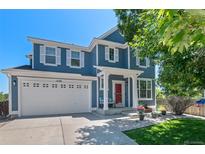 Charming two-story home featuring blue siding, white trim, a two-car garage, and a beautifully landscaped front yard at 12491 E 106Th Pl, Commerce City, CO 80022