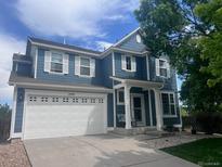 Charming blue two-story home featuring a pristine white garage door, shuttered windows, and a welcoming covered entryway at 12491 E 106Th Pl, Commerce City, CO 80022