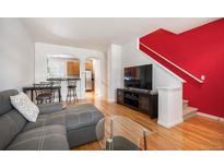 Bright living room featuring hardwood floors, a stylish gray couch and staircase with a red accent wall at 767 Roslyn St # 20, Denver, CO 80230