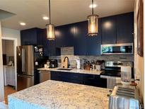 Modern kitchen featuring stainless steel appliances, a granite countertop island, and stylish lighting fixtures at 1778 S Lee St, Lakewood, CO 80232