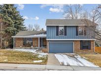 Charming two-story home featuring a mix of blue siding and brick with an attached two car garage at 8836 E Phillips Pl, Centennial, CO 80112