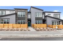 Modern townhouse featuring gray siding, stone accents, large windows, and inviting landscaping at 9468 W 58Th Ln # C, Arvada, CO 80002