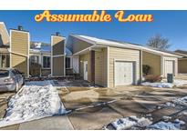 Inviting exterior of a townhome featuring a private garage and a well-maintained lawn partially covered with snow at 11860 Harrison St, Thornton, CO 80233