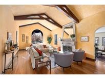 Spacious living room with vaulted ceilings, wood beams, fireplace, and hardwood floors at 6 Ivy Ln, Denver, CO 80220