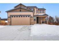 Two-story house with a beige exterior, stone accents, and a three-car garage at 17395 Leisure Lake Dr, Monument, CO 80132