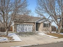 Charming brick home featuring an attached two-car garage and well-maintained front yard at 14485 Gaylord St, Thornton, CO 80602