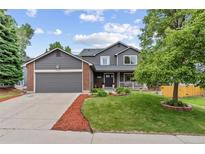 Charming two-story home featuring a well-manicured lawn, gray siding, brick accents and an attached two-car garage at 19935 E Stanford Dr, Centennial, CO 80015